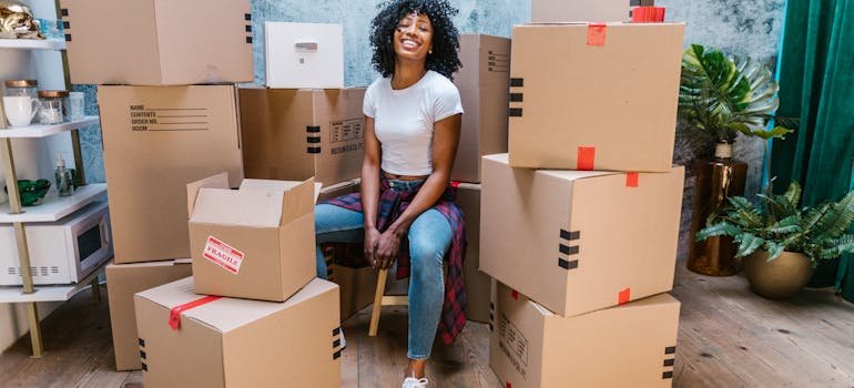 A happy woman sitting between moving boxes 