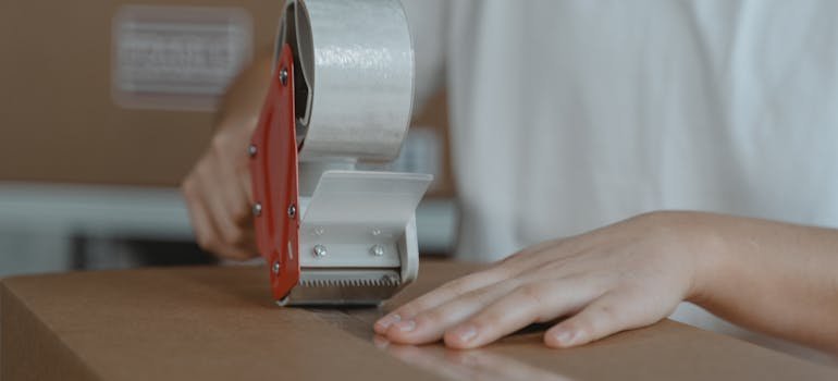 A person sealing a moving box 