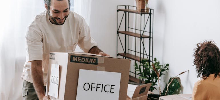 A man carrying a moving box labeled office