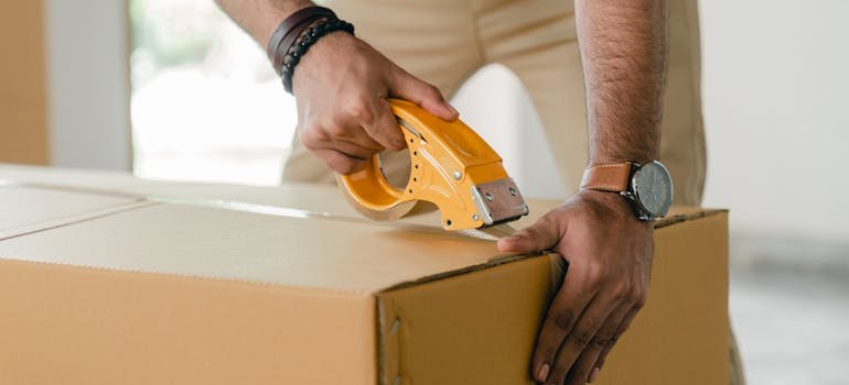 A man sealing a moving box 
