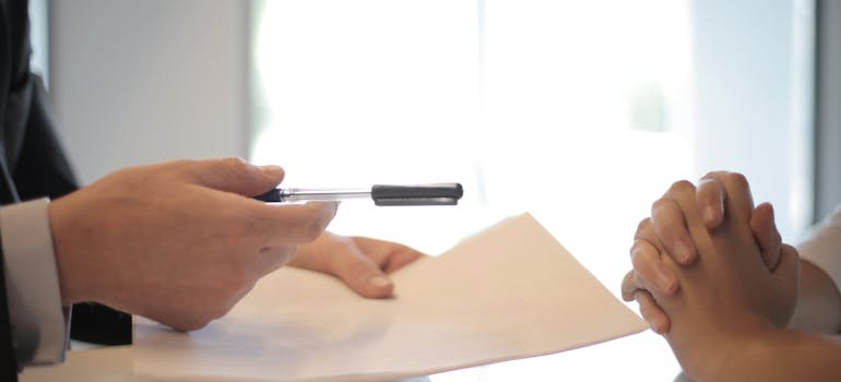 A person holding a pen and a paper signing a document about Schertz real estate market.