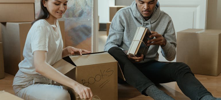 A couple packing books into the moving box