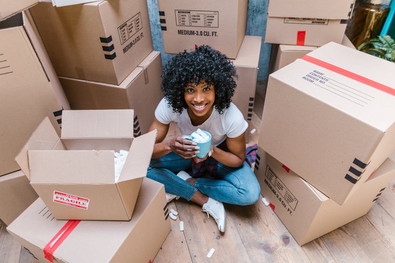A woman sitting between boxes and thinking about the creative uses for leftover packing supplies