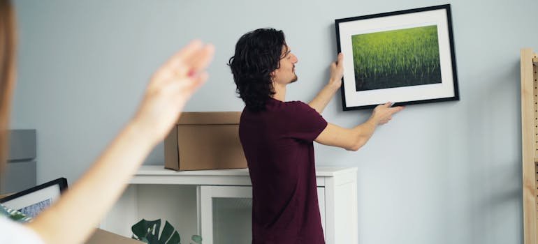 A man putting a picture on the wall