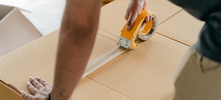 A person sealing a moving box