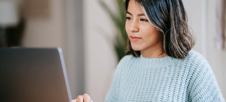 A woman using a laptop to research San Antonio real estate market for smaller homes