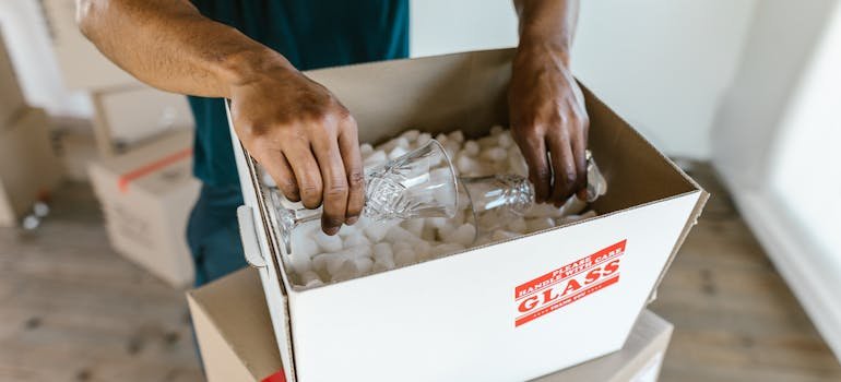 A mover using a moving box to pack fragile kitchen items
