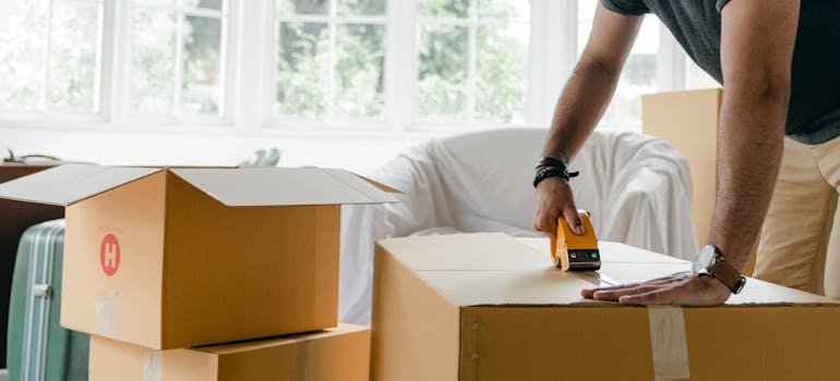 A person sealing a moving box