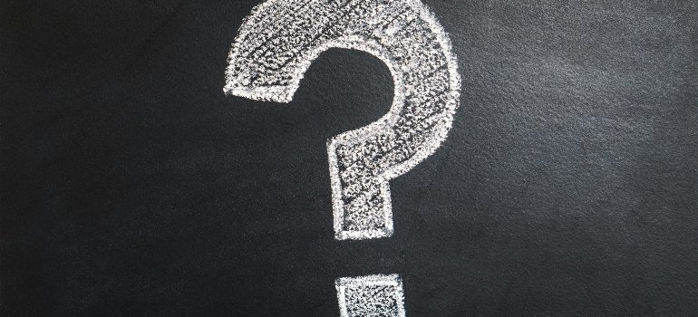 Large white question mark on a blackboard, representing the most important questions to ask before hiring a moving company.