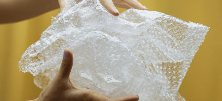 Hands holding bubble wrap used for protecting high-end furniture during a move in San Antonio, highlighting proper packing materials.