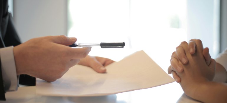 Person reviewing paperwork and signing a contract, highlighting key questions to ask before hiring a moving company.