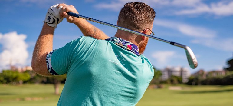 A man swinging a golf club on a sunny course, highlighting outdoor recreation while living in Fair Oaks Ranch.