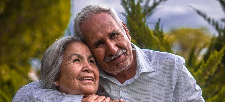 Smiling seniors hugging in safe and affordable cities in Bexar County for retirement