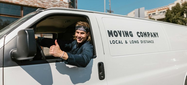 Mover giving a thumbs-up from a van, symbolizing business relocation services in cities near San Antonio for young entrepreneurs.