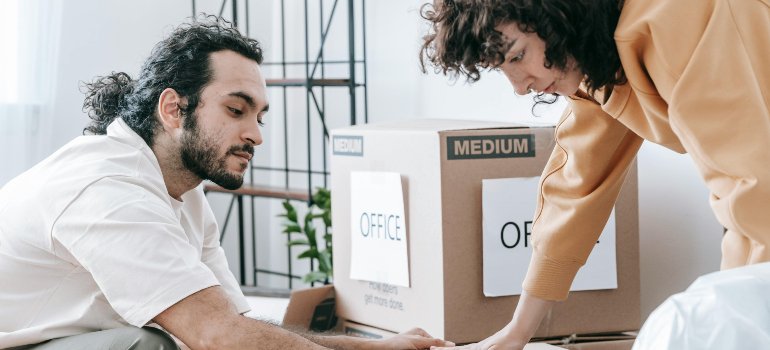 Young professionals packing office boxes for a business move to one of the cities near San Antonio for young entrepreneurs.