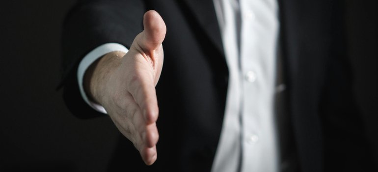 Person in a business suit reaching out for a handshake.