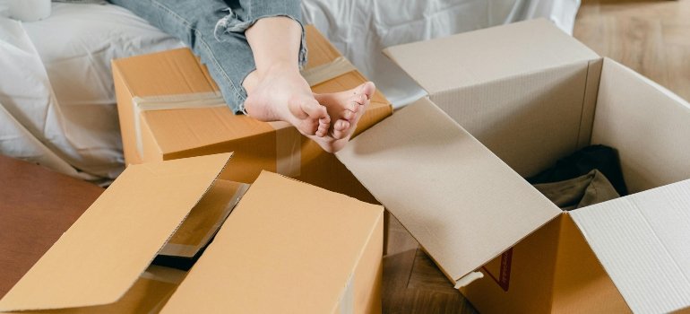 Person with bare feet resting on cardboard boxes while taking a break from unpacking.