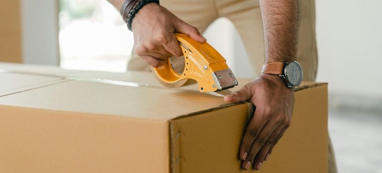 Man taping a moving box after learning how to pack your library for the move