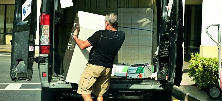 Man unloading a moving truck after relocating vintage furniture