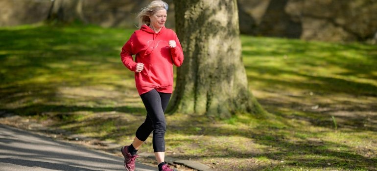 A girl in a red hoodie and black leggings jogging, showing the energy of lively cities in Bexar County for an active lifestyle.