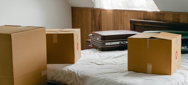 Bedroom with suitcases and cardboard boxes on the bed — What to Do If Your Furniture Gets Damaged During a Move.