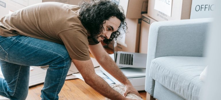 A man is wrapping a rug for safer relocation.