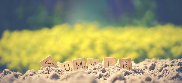 Word “SUMMER” spelled with Scrabble tiles in sand, representing the popular time to move to Castle Hill.