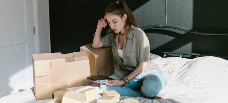 A woman sitting on a bed using a digital tablet to request a free moving quote from professional movers in Spring Branch.