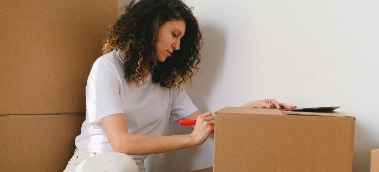 Woman Writing Labels on Brown Box