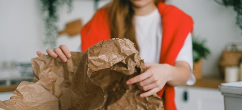 Woman holding a paper to fill up the gaps while she prepares to pack pictures and paintings when moving