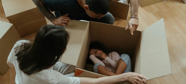 the girl lies in a cardboard box while her parents watch