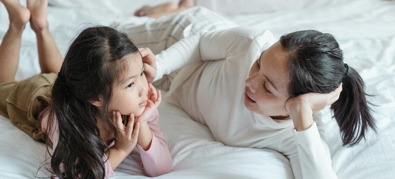 Photo of Woman and Girl Talking While Lying on Bed