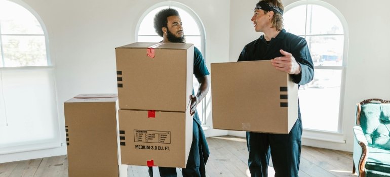 Men Carrying Cardboard Boxes while Having a Conversation