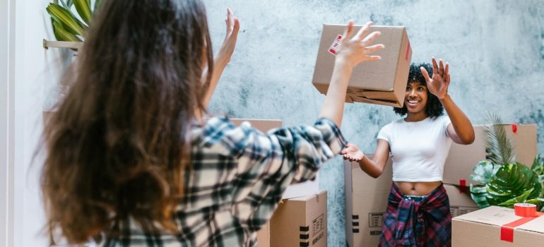 Woman playfully throwing a moving box to a friend while working with friendly Martinez movers San Antonio TX during a home move.