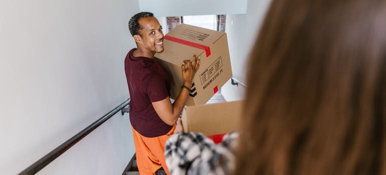 a man carries a cardboard box and walks down the stairs