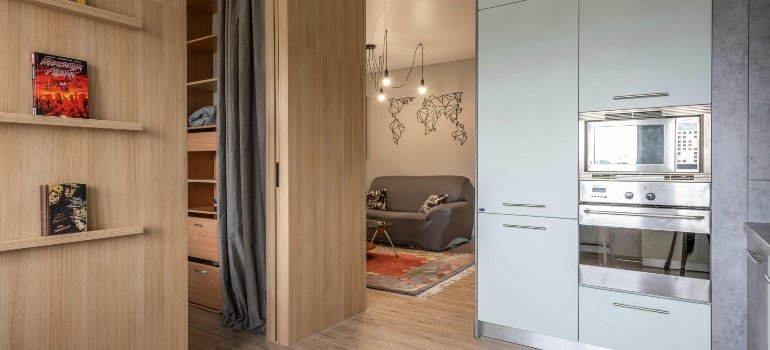 House with cupboards in kitchen near bookshelves and living room