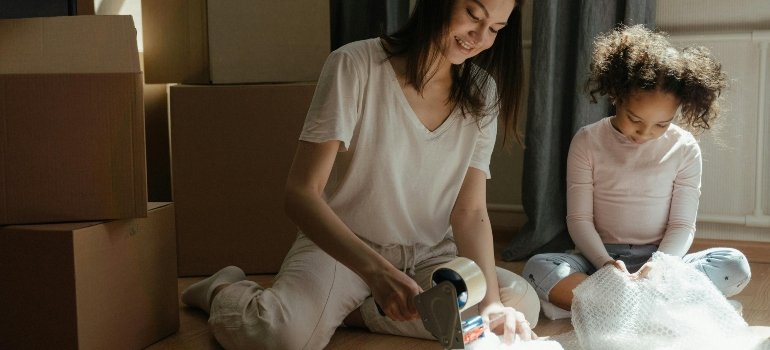 Mother and child wrapping breakable household items, demonstrating how to pack fragile things safely when moving.