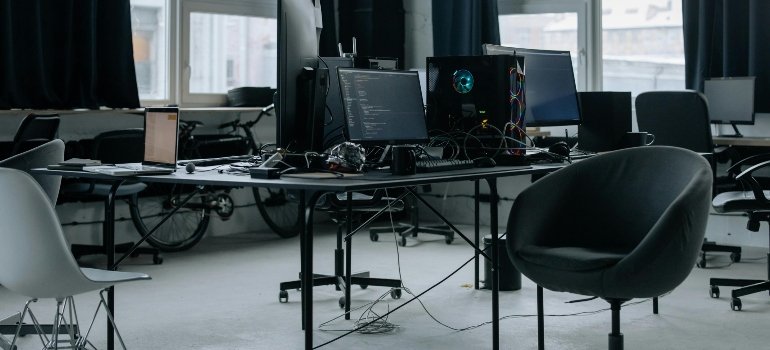 Office desks and computers arranged and labeled using a business move checklist before commercial relocation.