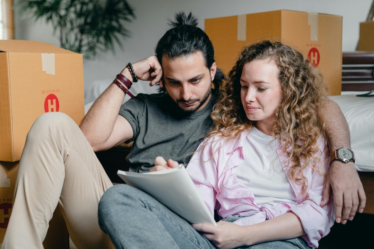Thoughtful couple writing in notebook while moving house