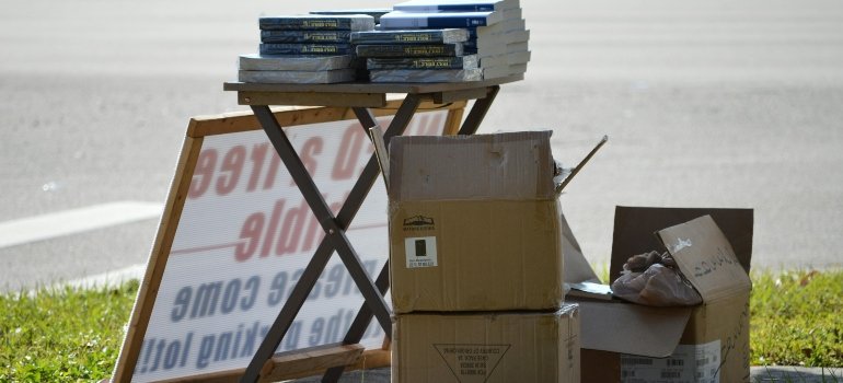 Yard sale setup with boxes and books as part of efforts to downsize for a move in Lytle.