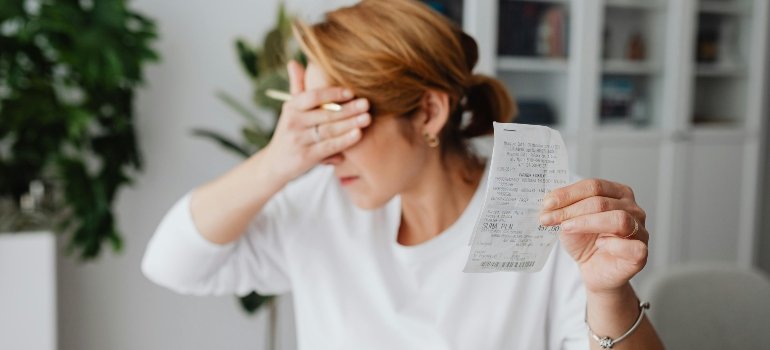 Woman checking a moving receipt while calculating relocation expenses.