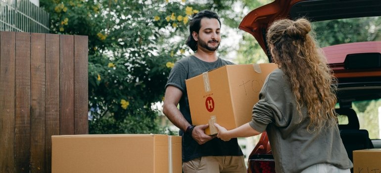 Couple lifting moving boxes into a car while planning the cost of moving in Cibolo.